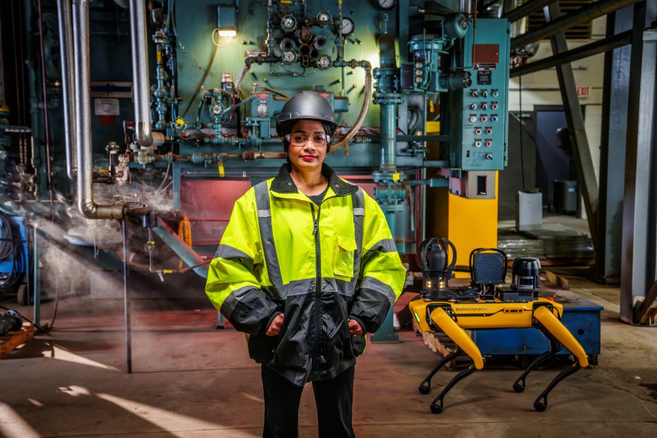 Reliability engineer standing beside Spot in an industrial facility