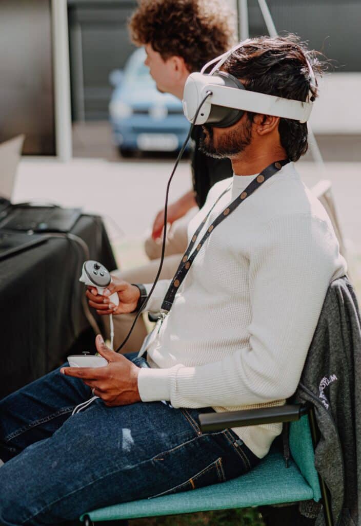 Man wearing a VR headset and using handheld controllers to remotely operate a Spot robot