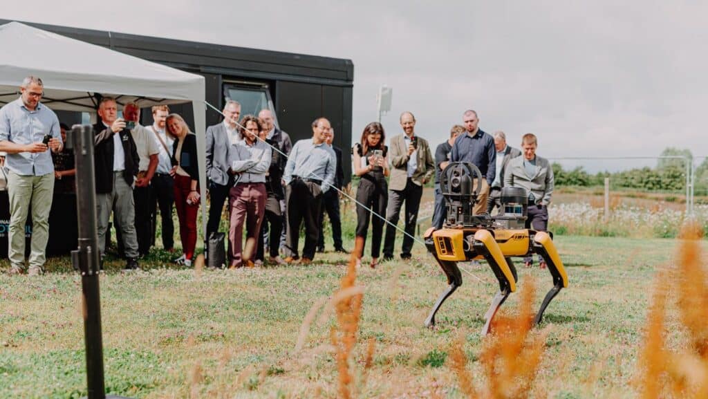 Group of people gathered around the robot Spot standing in a field